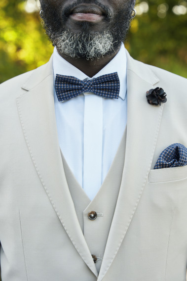 Zoom Costume SUAT couleur craie. Avec nœud papillon et poche bleus foncés et pins fleur.