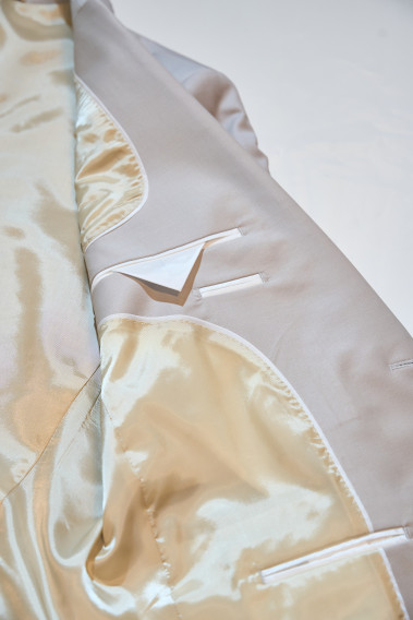 Zoom sur l’intérieur de la veste de costume SUAT couleur craie. La doublure est beige clair, elle comporte 3 poches intérieures.