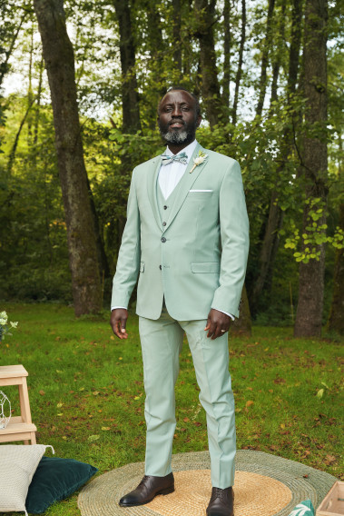 Homme de face en costume SUAT couleur vert d'eau 3 pièces dans un parc.
