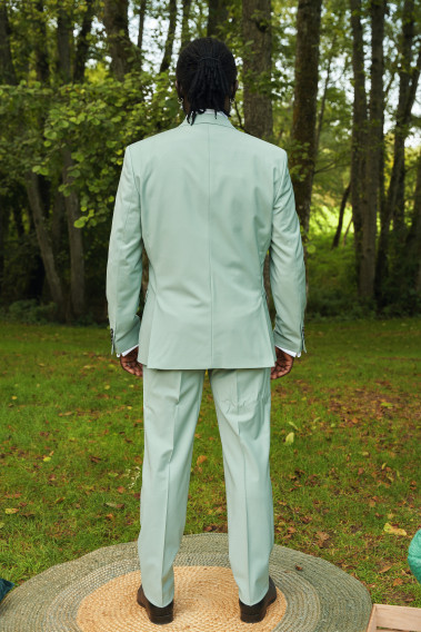 Homme de dos en costume SUAT couleur vert d'eau. Il porte des chaussures marrons.