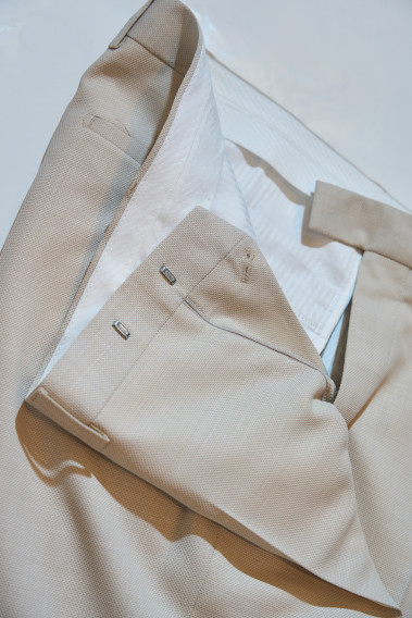 Zoom sur l’intérieur du pantalon du costume SUAT couleur beige. La doublure est blanche.