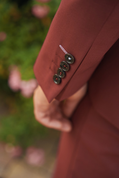 Zoom sur la manche du costume SUAT couleur framboise. Elle comporte 4 boutons marrons.