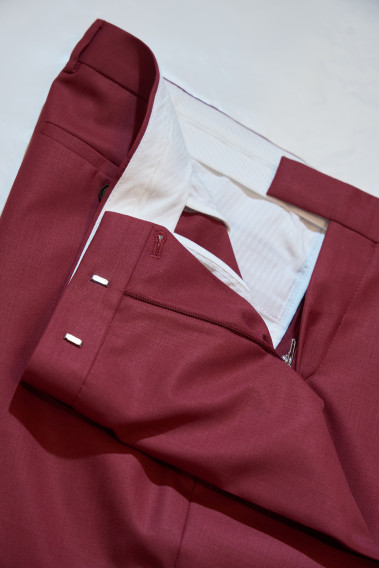Zoom sur l’intérieur du pantalon du costume SUAT couleur framboise. La doublure est blanche.
