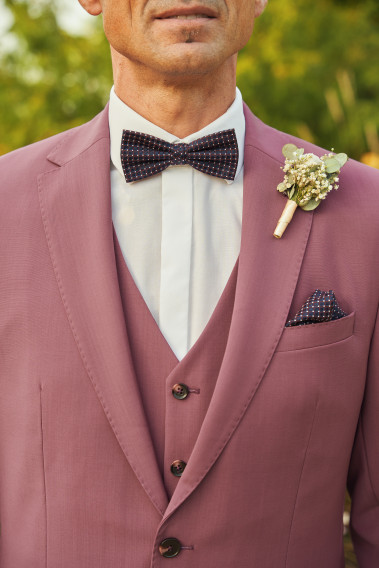 Costume SUAT couleur fushia. Plan sur le nœuds  papillon et la poche à motif bleu foncé.