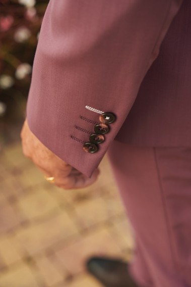Zoom sur la manche du costume SUAT couleur fushia. Elle comporte 4 boutons marrons.
