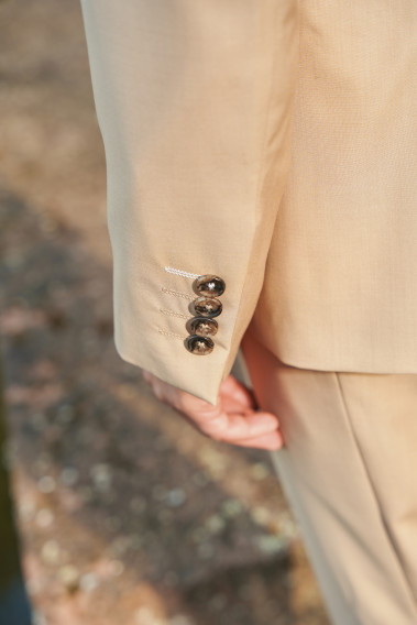 Costume SUAT beige sable. Plan détail sur les boutons de couleur marron.