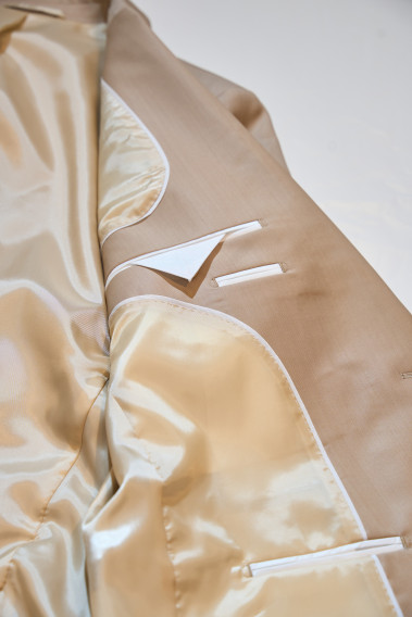 Zoom sur l’intérieur de la veste de costume SUAT couleur beige sable. La doublure est beige, elle comporte 3 poches intérieures.
