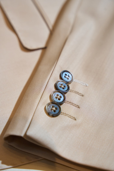 Costume SUAT beige sable. Plan détail sur les boutons de couleur marron.