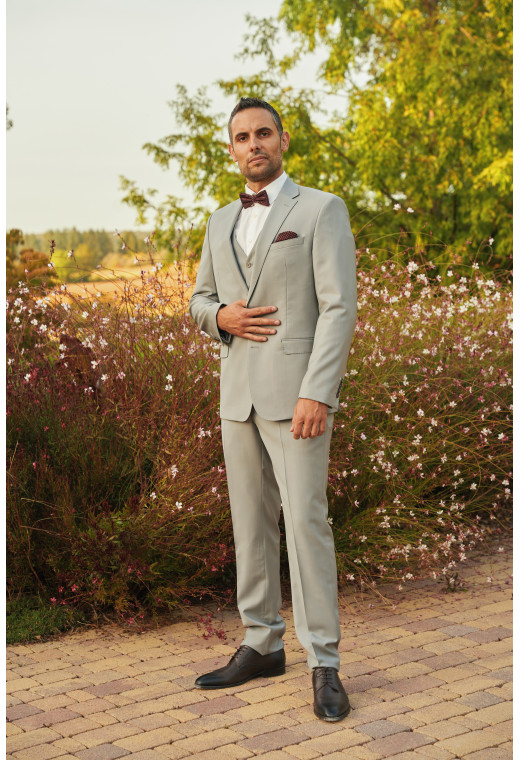 Homme de face en costume SUAT gris clair 3 pièces dans  une cours.