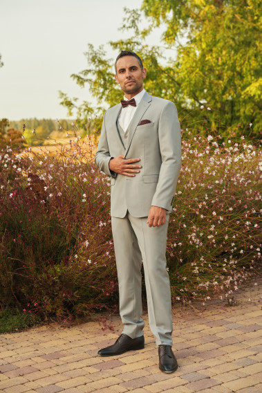 Homme de face en costume SUAT gris clair 3 pièces dans  une cours.