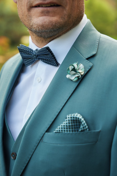Costume SUAT vert bleuté. Plan sur le nœuds  papillon bleu foncé rayé  et la poche à motif vert.