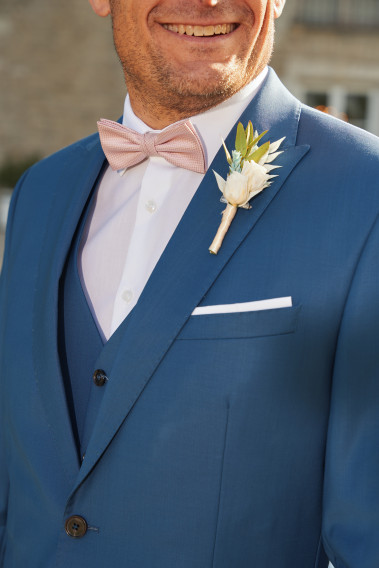 Costume SUAT bleu. Plan sur le nœuds  papillon rose et le pins bouquet de fleur.