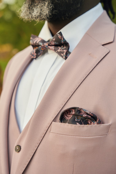 Costume SUAT rose pâle. Plan sur le nœuds  papillon et la poche à motif noir.