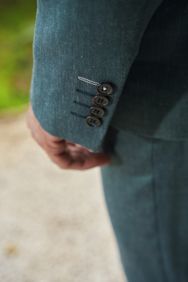 Zoom sur la manche du costume SUAT couleur vert. Elle comporte 4 boutons marrons.