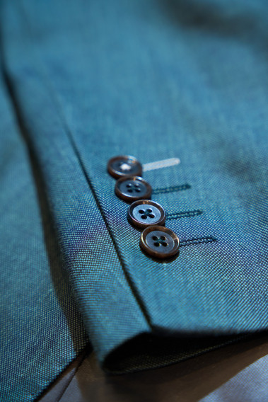 Zoom sur la manche du costume SUAT couleur vert. Elle comporte 4 boutons marrons.