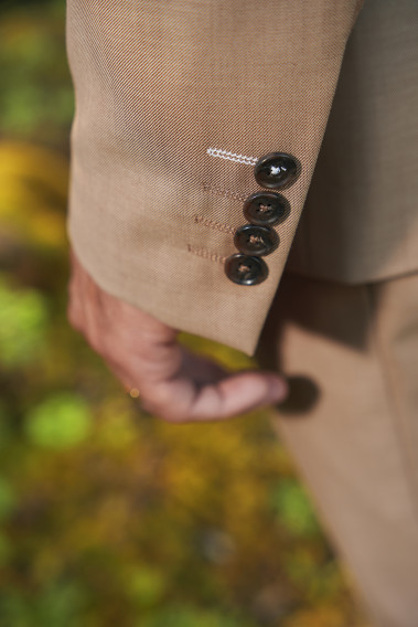 Zoom sur la manche du costume SUAT couleur beige foncé. Elle comporte 4 boutons marrons.