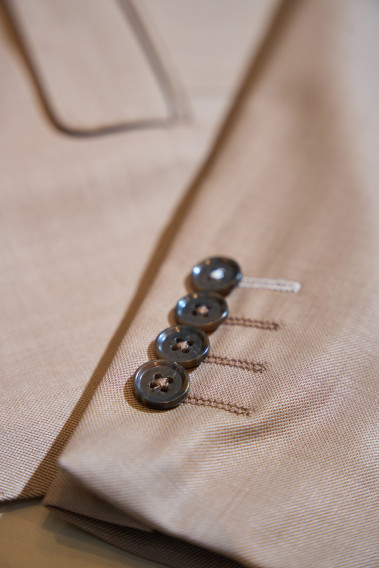 Zoom sur la manche du costume SUAT couleur beige foncé. Elle comporte 4 boutons marrons.
