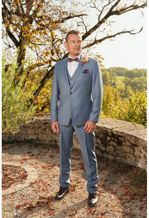 Homme de profil en costume SUAT couleur bleu orage 3 pièces dans une cours.