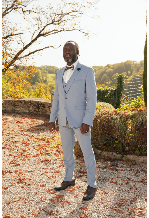Homme de face en costume SUAT couleur bleu grisé dans une cours.