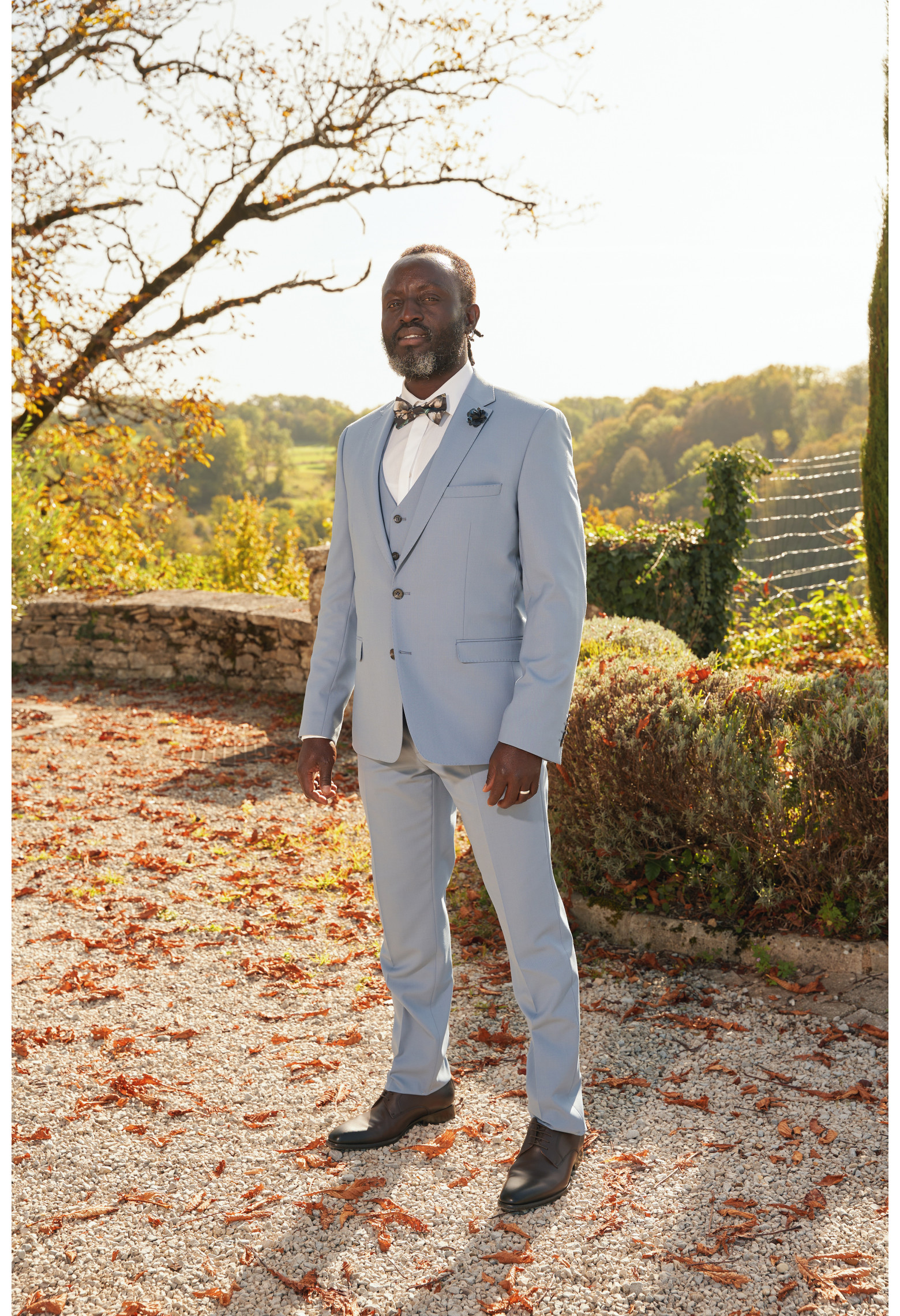 Homme de face en costume SUAT couleur bleu grisé dans une cours.