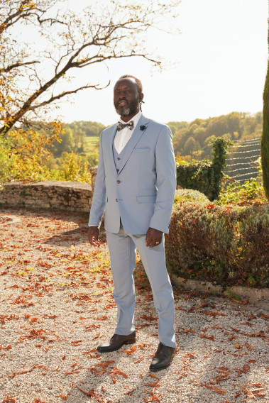 Homme de face en costume SUAT couleur bleu grisé dans une cours.