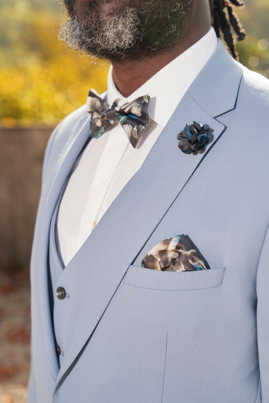 Costume SUAT bleu grisé. Plan sur le nœuds  papillon et la poche à motif noir.