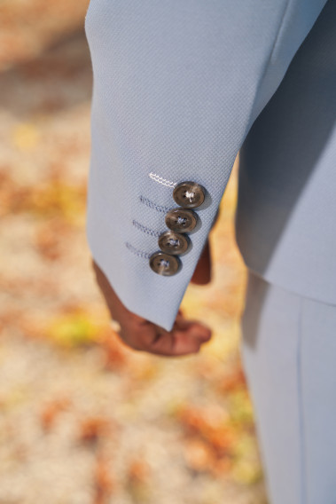 Zoom sur la manche du costume SUAT couleur bleu grisé. Elle comporte 4 boutons noirs.
