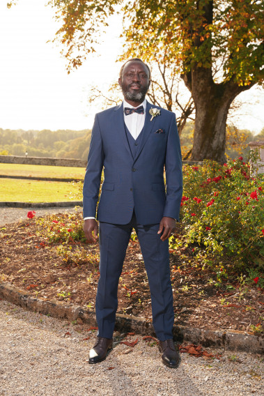 Homme de face en costume SUAT couleur marine à carreaux 3 pièces dans un jardin.