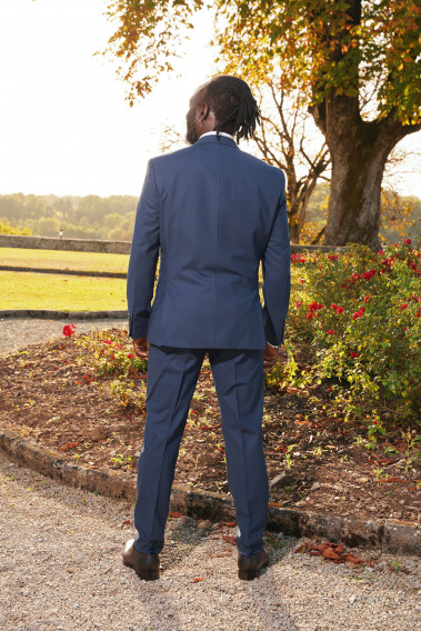 Homme de dos en costume SUAT couleur marine à carreaux 3 pièces dans un jardin. Il porte des chaussures marrons.