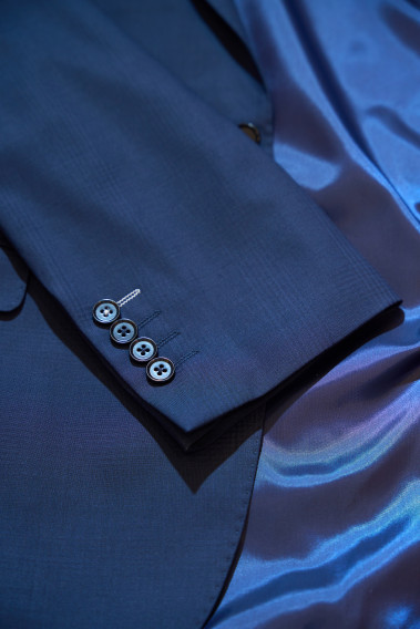 Zoom sur la manche de la veste SUAT couleur marine à carreaux. Elle comporte 4 boutons.