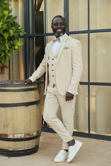 Homme portant la veste TROPICAL beige. Elle comporte une poche poitrine et 2 poches plaquées.