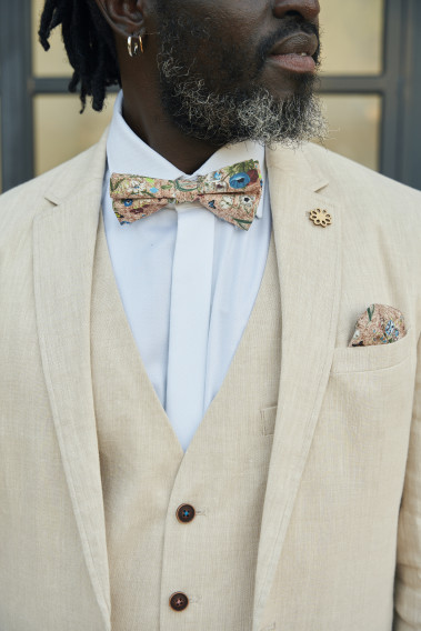 Zoom sur la veste TROPICAL beige. L'homme porte une nœuds papillon et un mouchoir de poche.