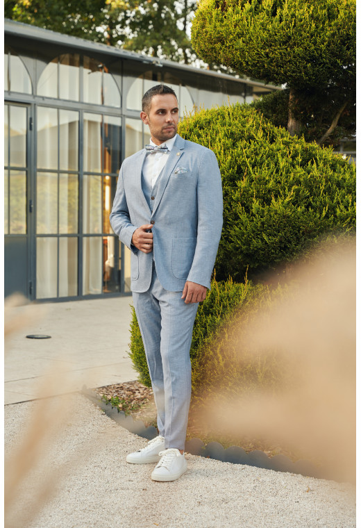 Homme portant la veste TROPICALW bleue. Elle comporte une poche poitrine et 2 poches plaquées.