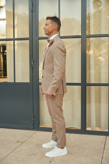 Homme de profil portant la veste TROPICALW brune. Elle comporte une poche poitrine et 2 poches plaquées.