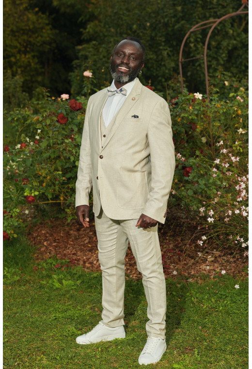 Homme portant la veste TROPICALW beige. Elle comporte une poche poitrine et 2 poches plaquées.