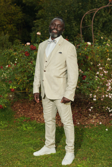 Homme portant la veste TROPICALW beige. Elle comporte une poche poitrine et 2 poches plaquées.