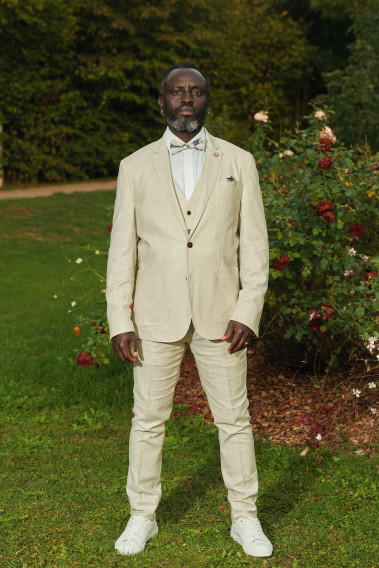 Homme portant la veste TROPICALW beige. Elle comporte une poche poitrine et 2 poches plaquées.