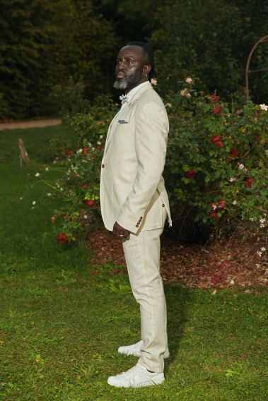 Homme de profil portant la veste TROPICALW beige. Elle comporte une poche poitrine et 2 poches plaquées.