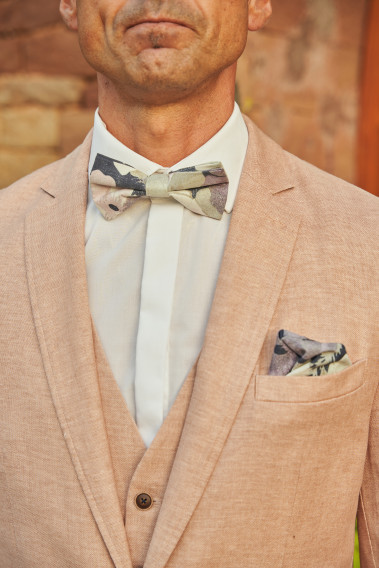 Zoom sur la veste GIORGIOVW rose. L'homme porte une nœuds papillon et un mouchoir de poche.