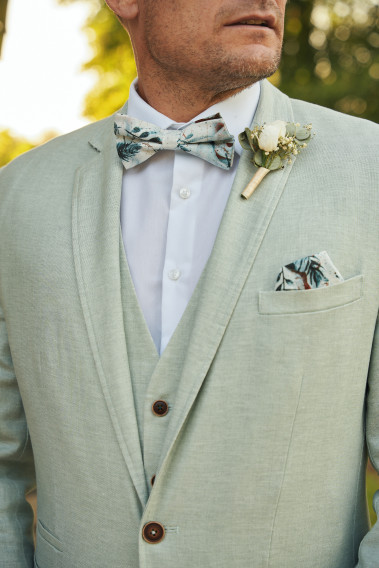 Veste GIORGIOVW vert pastel en gros plan avec le noeud papillon et la boutonnière. Costume en mélange de lin.